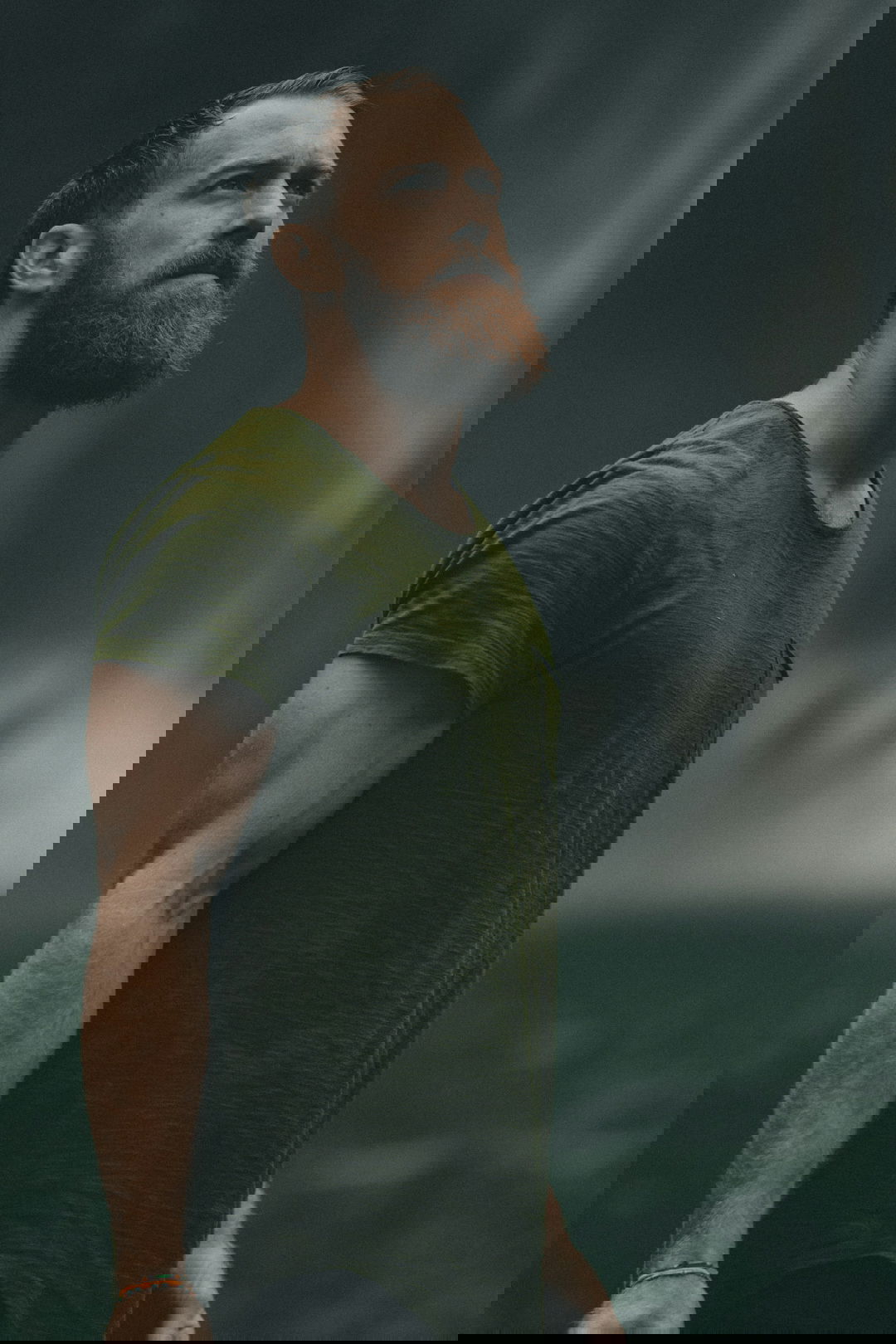 man wearing green crew-neck t-shirt looking upwards